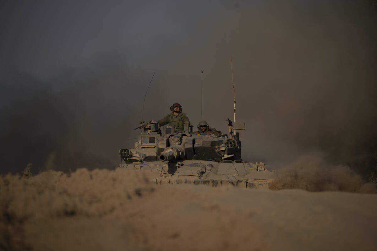 Israeli soldiers move on the top of a tank near the Israeli-Gaza border, as seen from southern ...