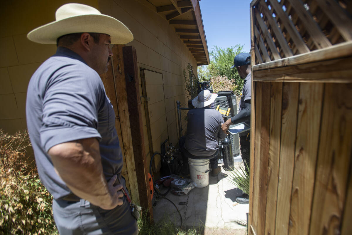 Curtis Coker, left, watches Steve Kendrick, center, and Dijon Sims, right, install a new HVAC u ...