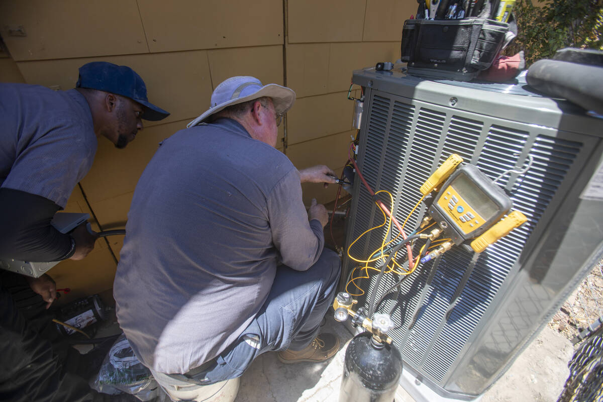 Dijon Sims, left, and Steve Kendrick, right, install a new HVAC unit at Kit Herron’s home Fri ...