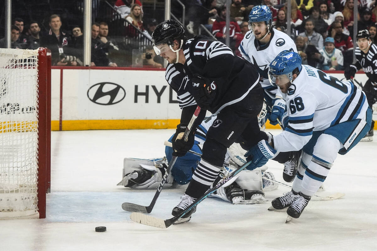 San Jose Sharks Mike Hoffman, right, reaches the puck before New Jersey Devils Alexander Holtz, ...