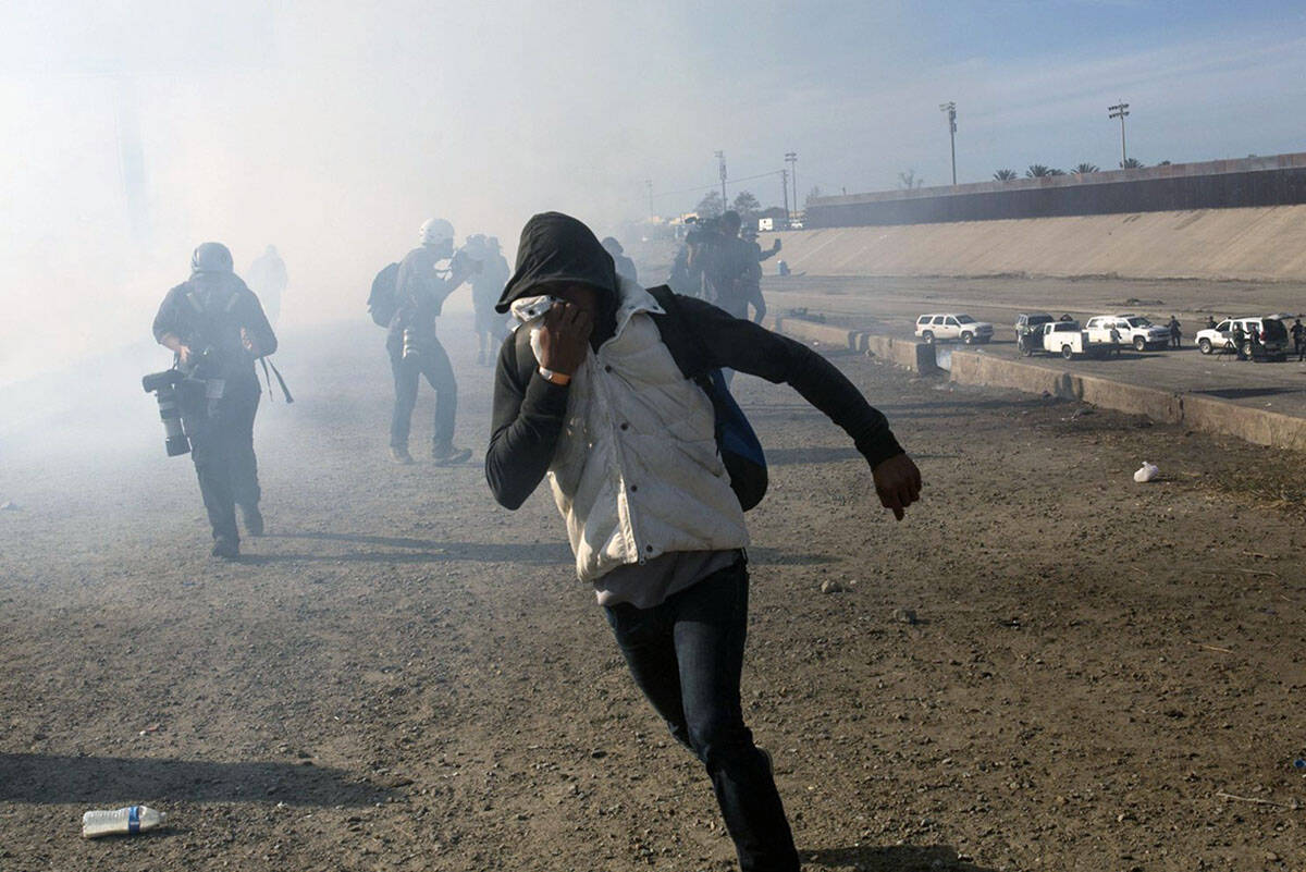 A migrant runs from tear gas launched by U.S. agents in Tijuana, Mexico. (AP Photo/Rodrigo Abd)