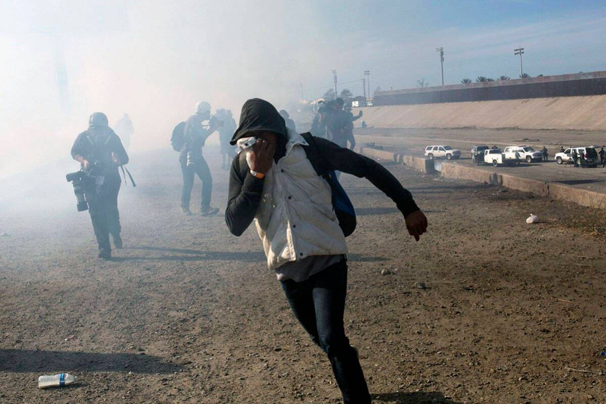 A migrant runs from tear gas launched by U.S. agents in Tijuana, Mexico. (AP Photo/Rodrigo Abd)