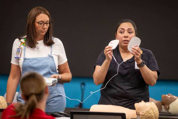 R.N. Jamie Hurley, left, and R.N. Xochitl Kambak, right, teach campers on how to use an automat ...
