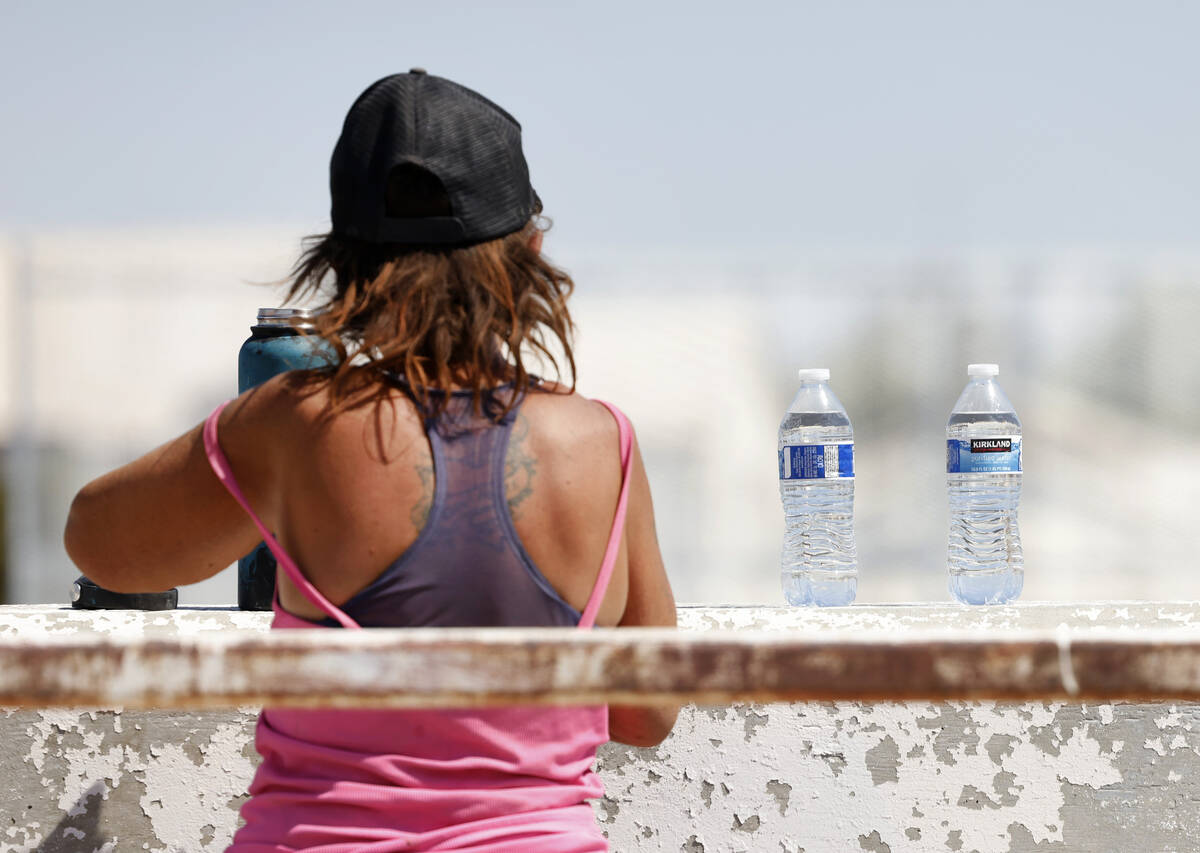 A homeless person fills out her water bottle, delivered by a Help of Southern Nevada outreach w ...