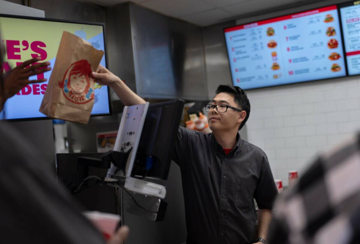 Lawrence Cheng, whose family owns seven Wendy's locations south of Los Angeles, hands an order ...