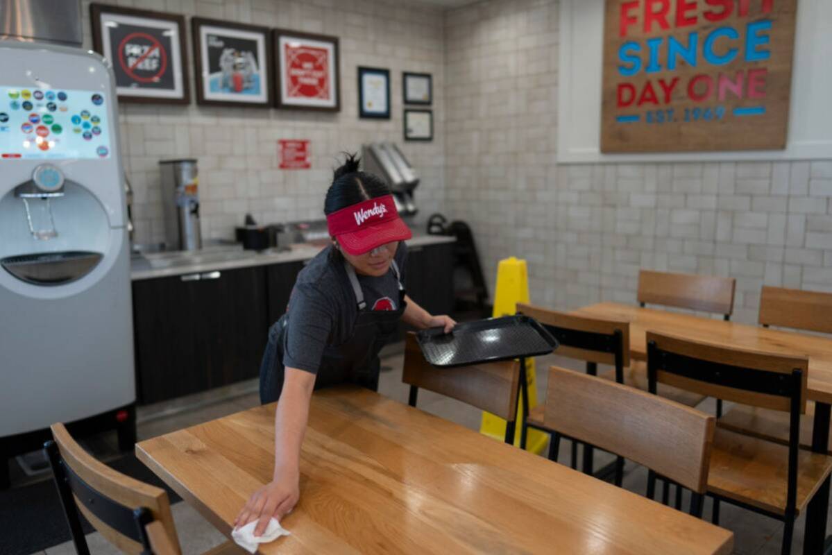 Part-time employee Adriana Ruiz, 18, cleans a table at a Wendy's restaurant owned by Lawrence C ...