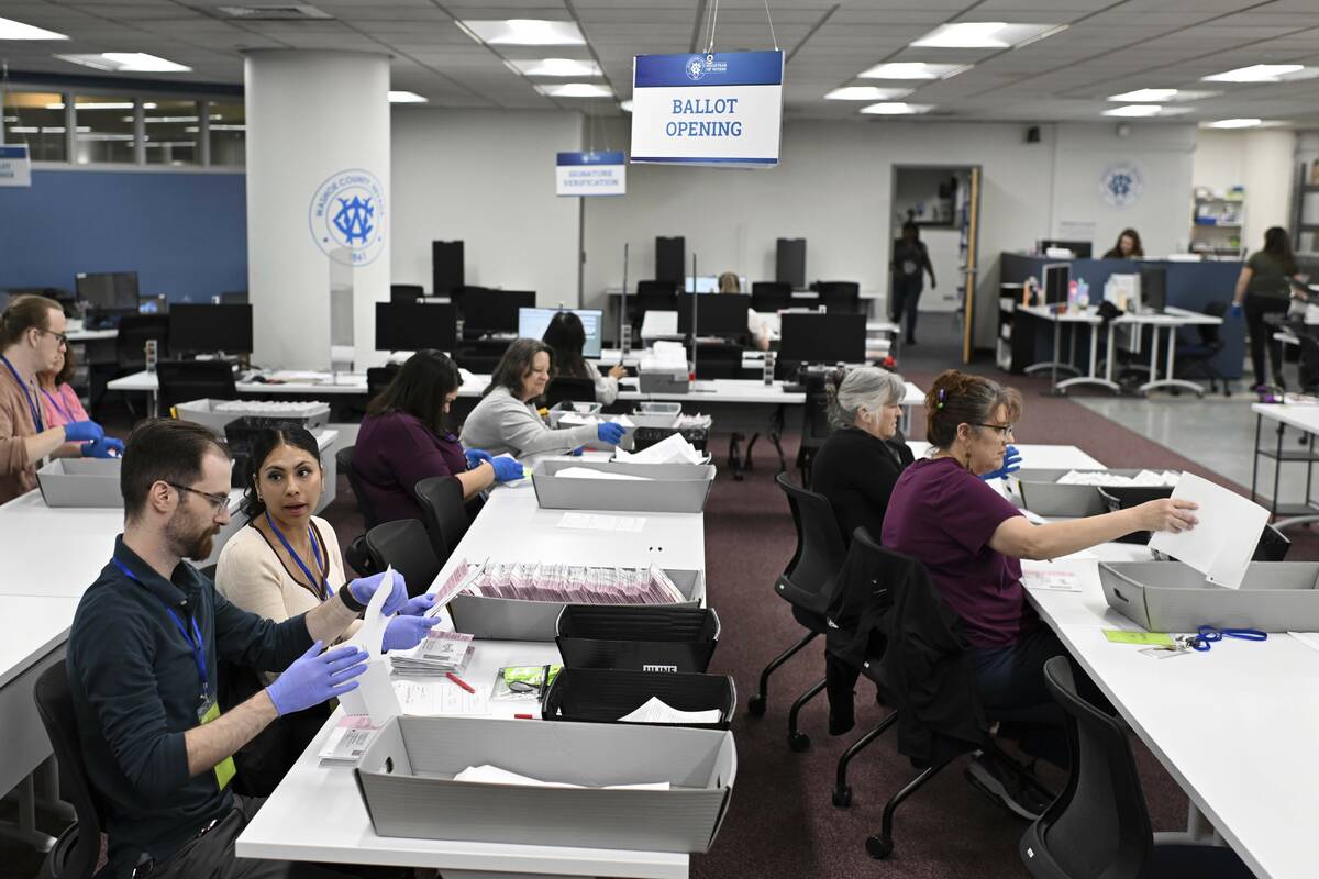 County employees open ballots in the ballot opening area of the mail ballot processing room at ...