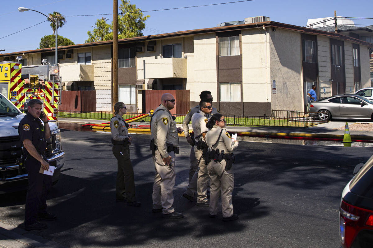 Las Vegas police look on as firefighters work to contain an apartment fire on Dumont Boulevard ...