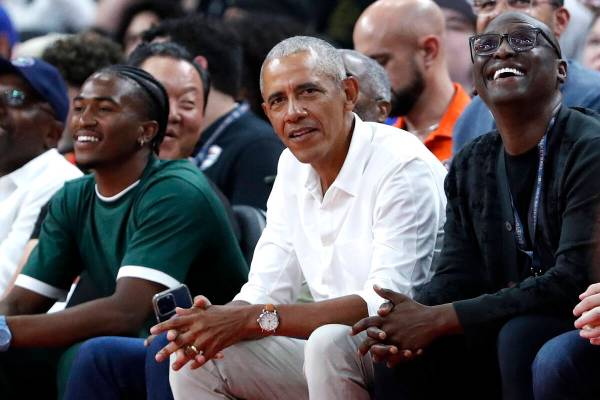 Former U.S. President Barack Obama, center, watches an exhibition basketball game between the U ...