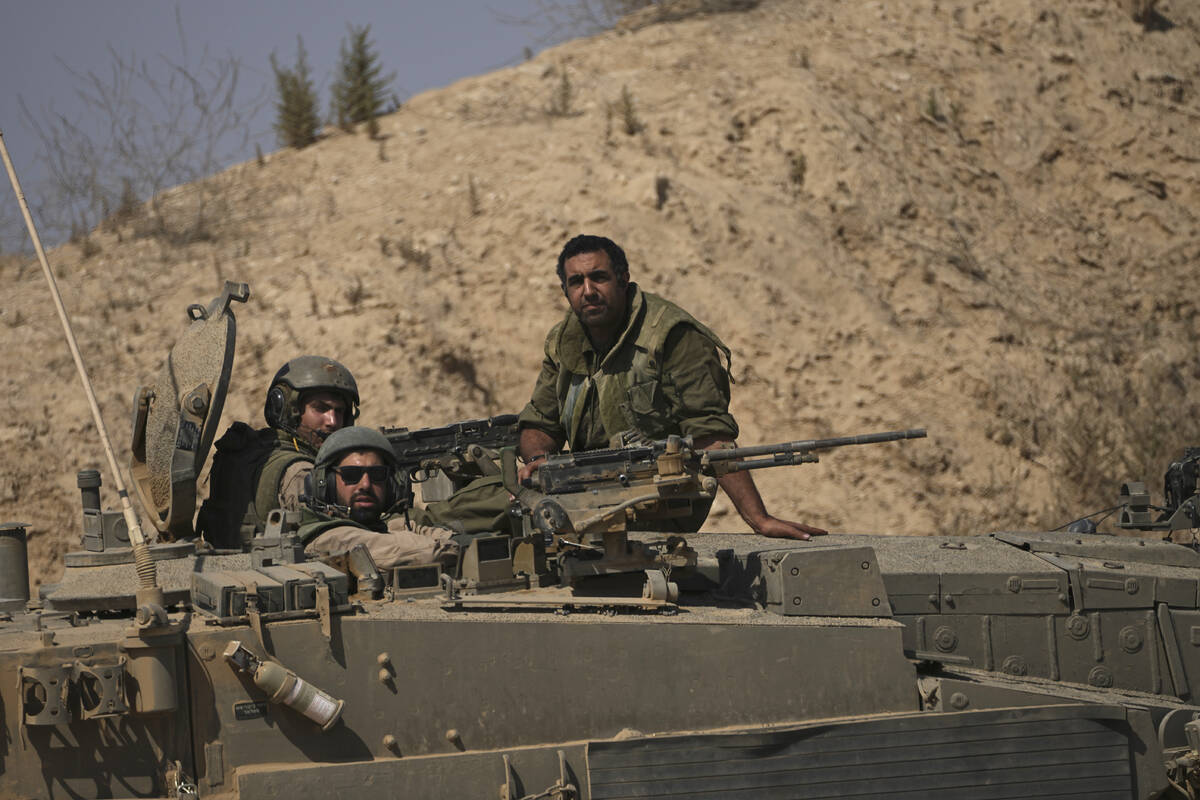 Israeli soldiers sit on their vehicle near the Israel-Gaza border in southern Israel, Friday, J ...