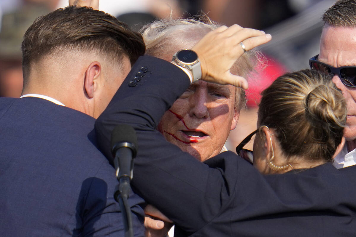 Republican presidential candidate former President Donald Trump is helped off the stage by U.S. ...