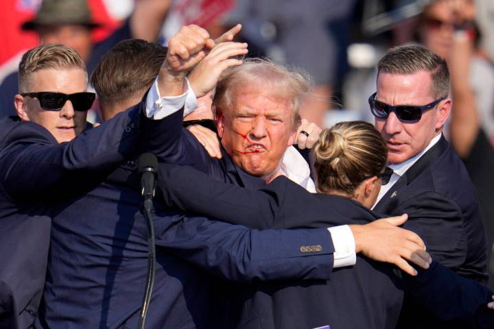 Republican presidential candidate former President Donald Trump pumps his fist as he is helped ...