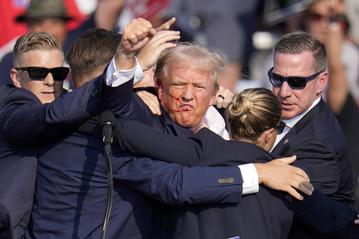 Republican presidential candidate former President Donald Trump pumps his fist as he is helped ...