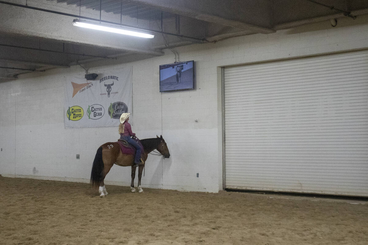 Katie Moore, of May, Texas, watches the competition broadcast on a television while warming up ...