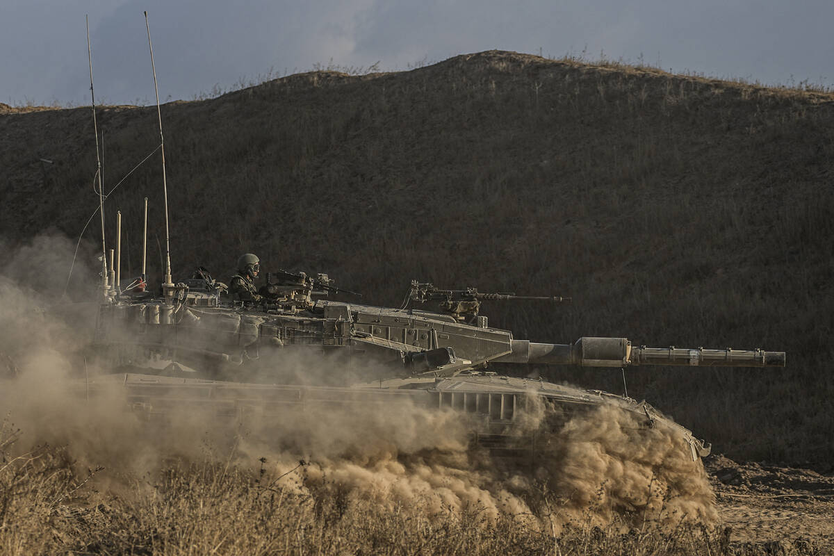 An Israeli soldier moves on the top of a tank near the Israeli-Gaza border, as seen from southe ...