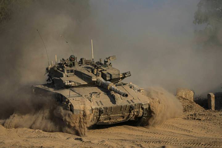 An Israeli soldier moves on the top of a tank near the Israeli-Gaza border, as seen from southe ...