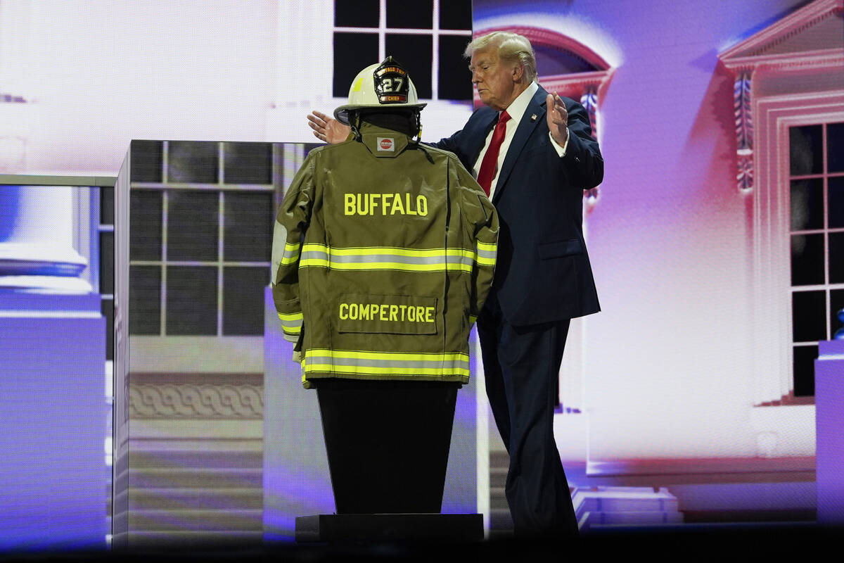 Republican presidential candidate former President Donald Trump stands next to the uniform of C ...