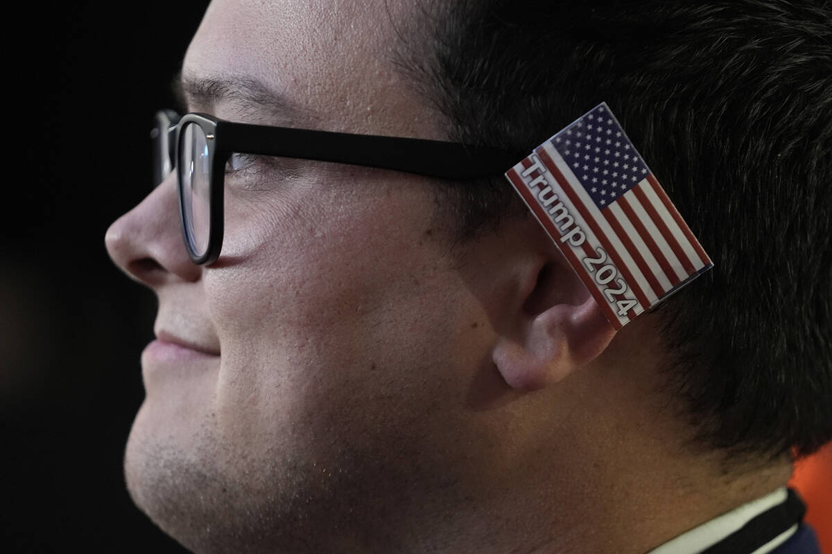 A delegate wearing a small American flag on his ear watches as Republican presidential candidat ...