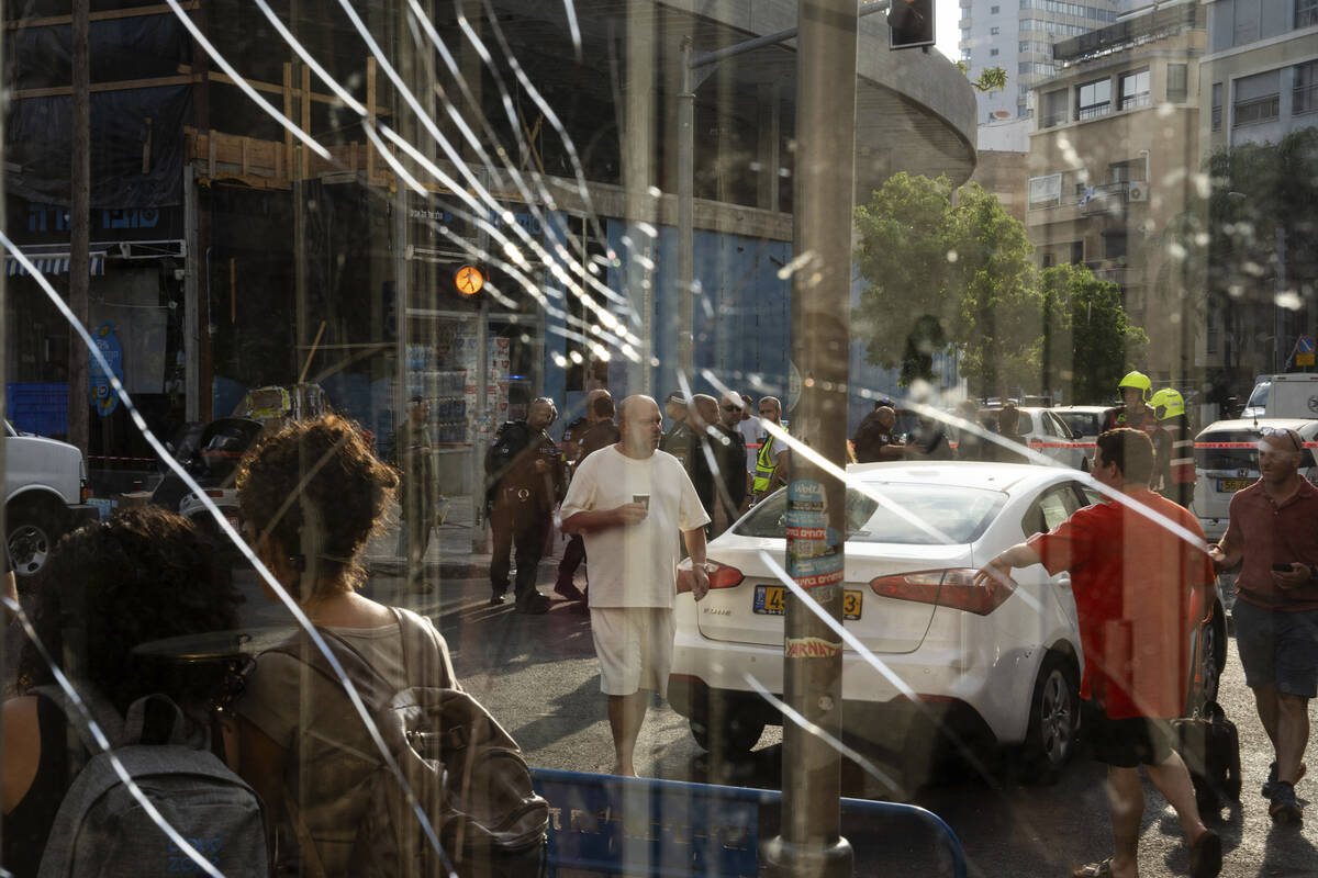 People are seen through a broken window next to the scene of an explosive drone attack in Tel A ...