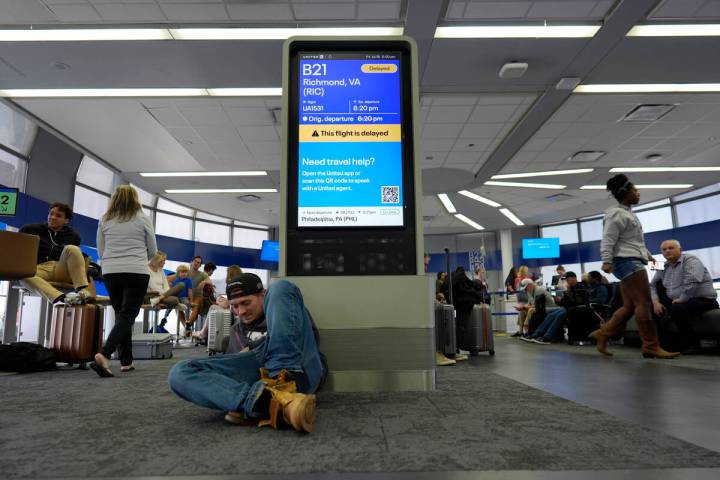 An information display near United gates shows a flight delay at Chicago O'Hare International A ...