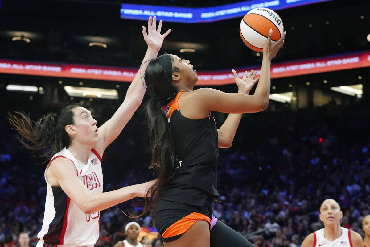 Angel Reece, front right, of Team WNBA, drives past Breanna Stewart, left, of Team USA, to scor ...