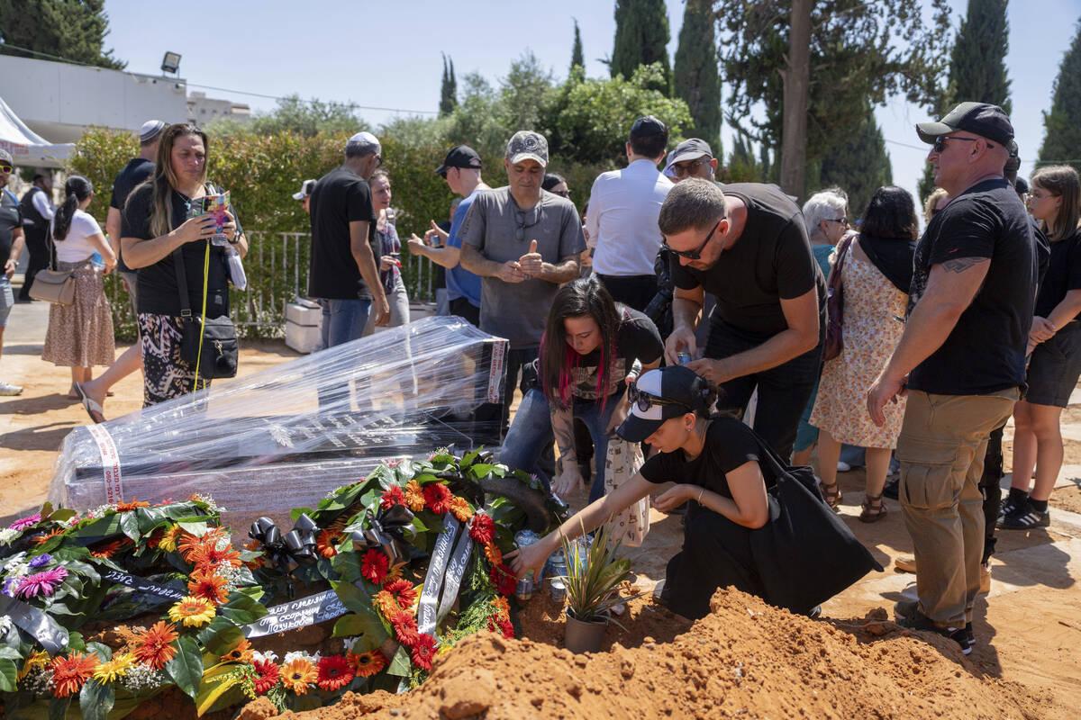 Family and friends of Yevgeny Ferde gather around his grave during his funeral at a cemetery in ...