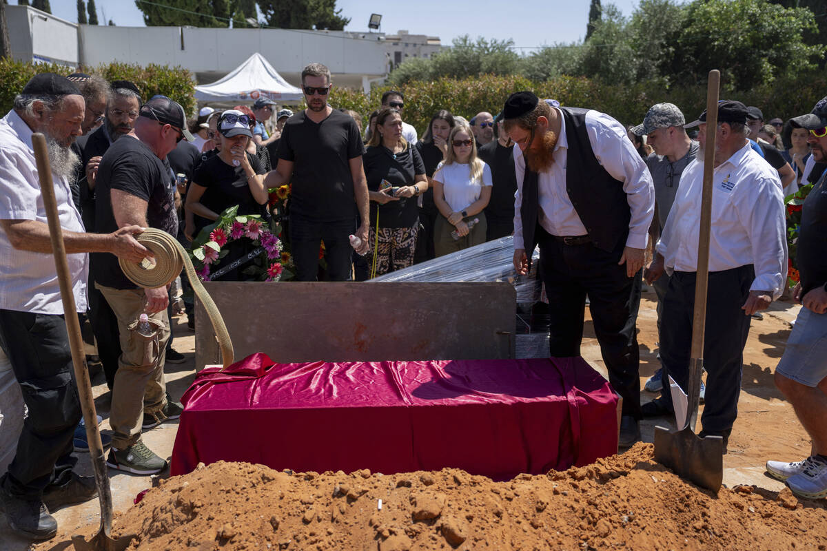 Family and friends of Yevgeny Ferde gather around his grave during his funeral at a cemetery in ...