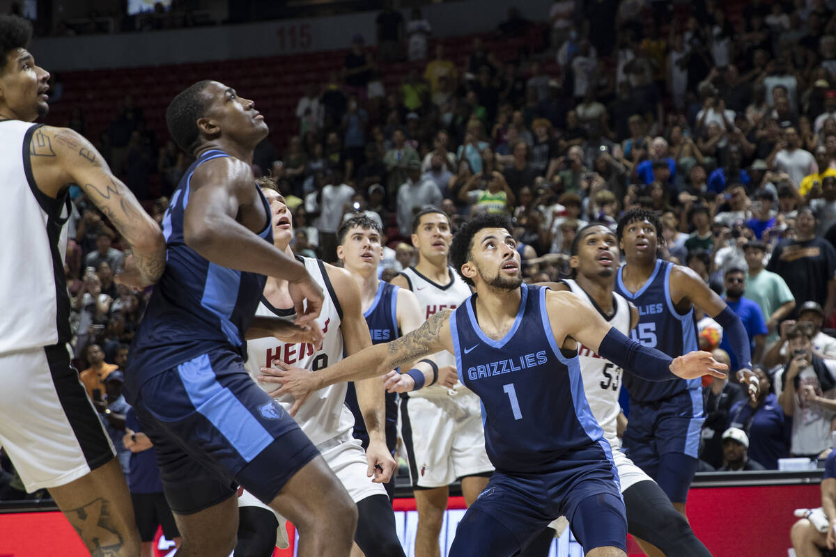 Members of the Memphis Grizzlies and Miami Heat watch the final shot go through the net, sealin ...