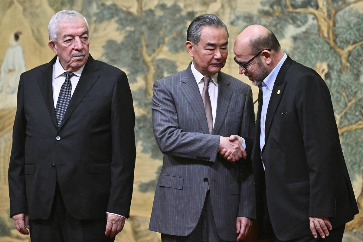 China's Foreign Minister Wang Yi, center, hosts an event for Mahmoud al-Aloul, left, vice chair ...