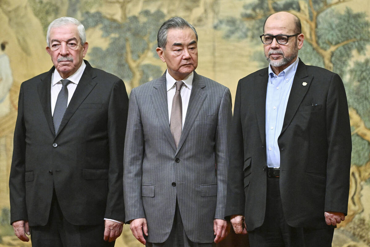 China's Foreign Minister Wang Yi, center, hosts an event for Mahmoud al-Aloul, left, vice chair ...