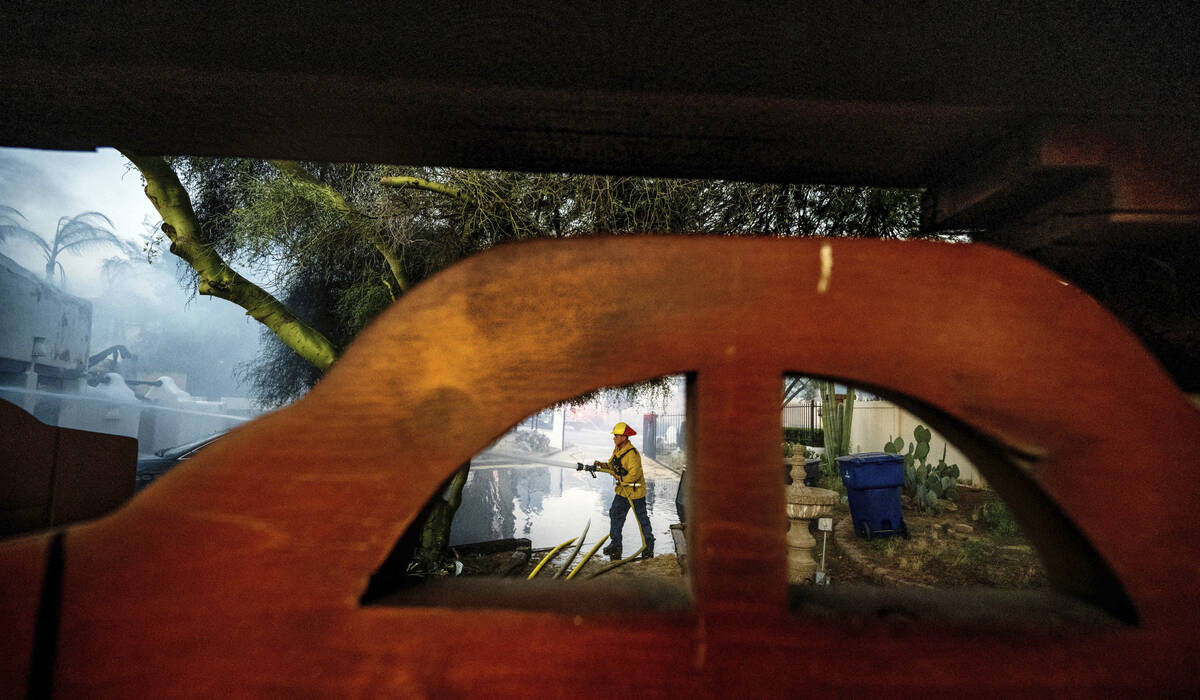 A firefighter hoses down the garage of Noel Piri's home that was destroyed by the Hawarden Fire ...