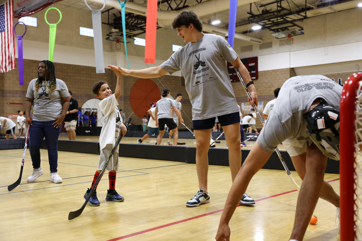 A draft prospect high-fives a local player during a street hockey camp at the Veterans Memorial ...