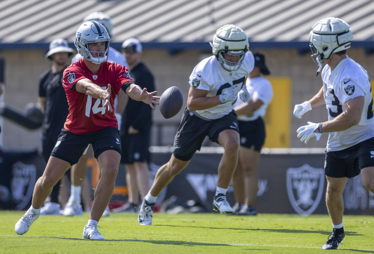 Raiders quarterback Carter Bradley (14) tosses the ball to running back Dylan Laube (23) during ...