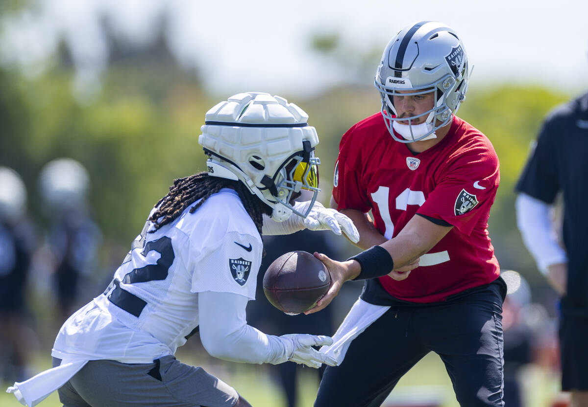 Raiders quarterback Aidan O'Connell (12) hands the ball off t6o running back Alexander Mattison ...