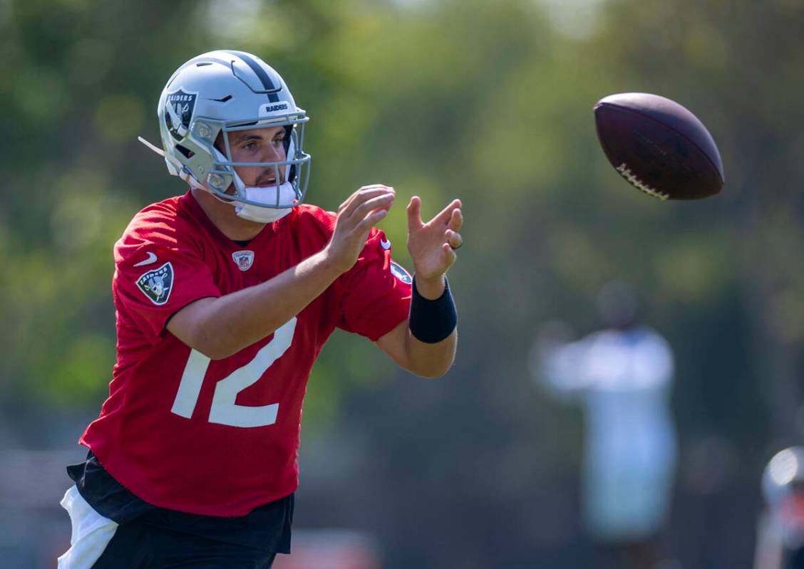 Raiders quarterback Aidan O'Connell (12) catches a ball during the first day of training camp a ...