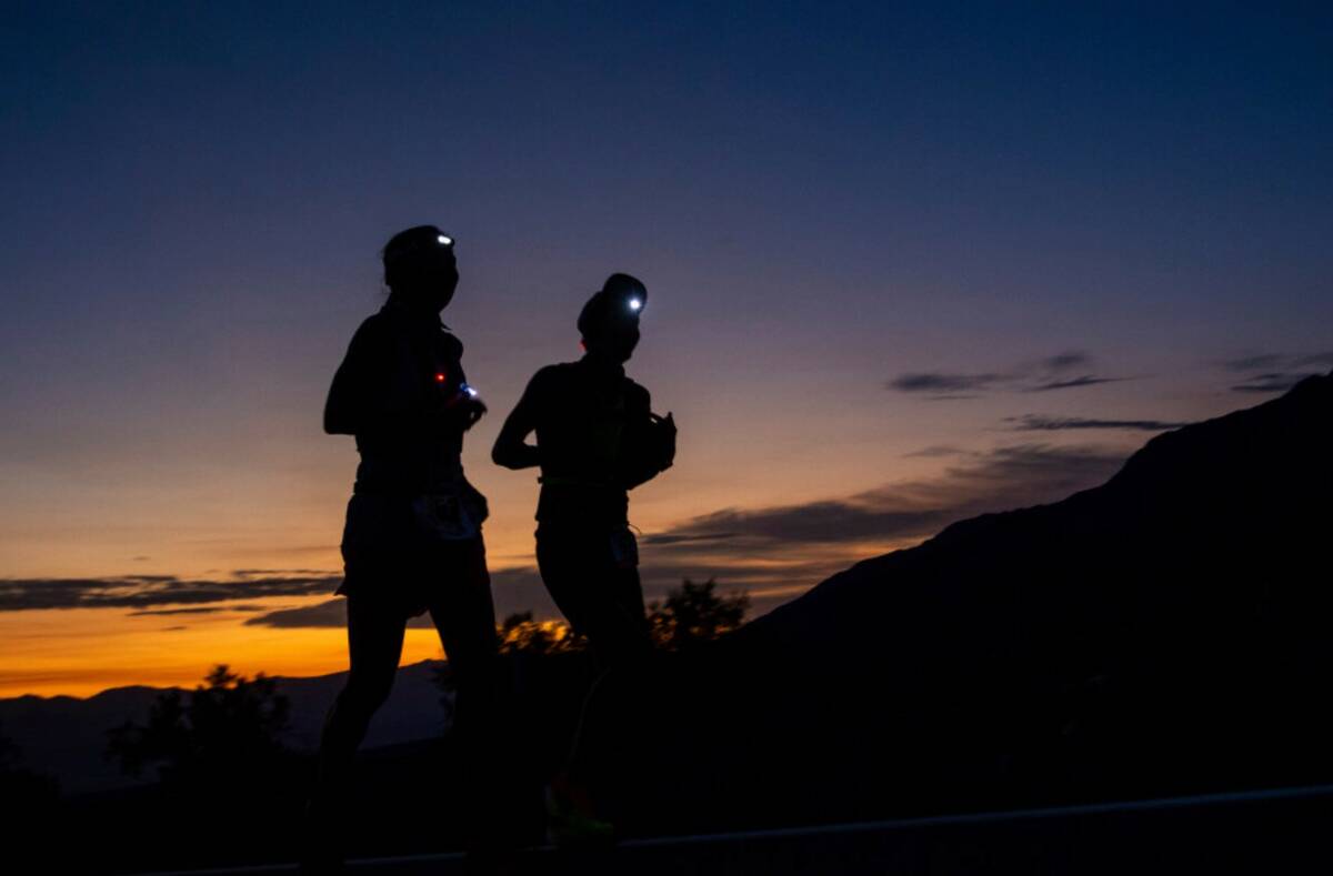 A runner and their pacer run as the sun rises behind them on California Route 190 during the Ba ...