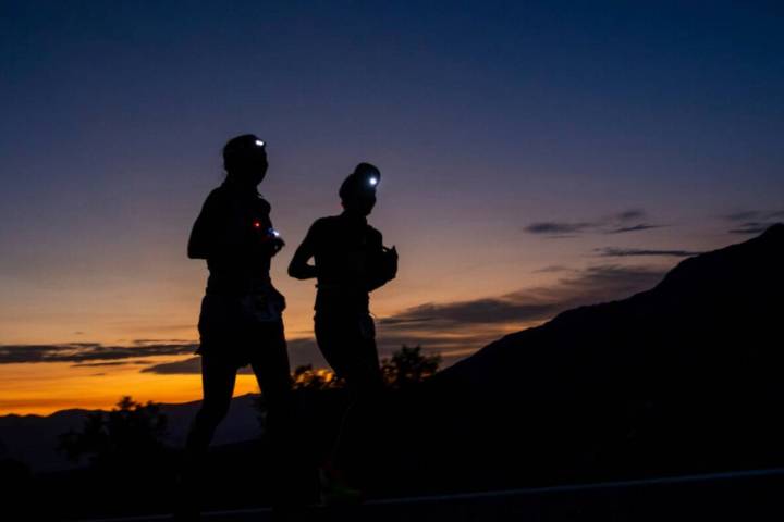 A runner and their pacer run as the sun rises behind them on California Route 190 during the Ba ...