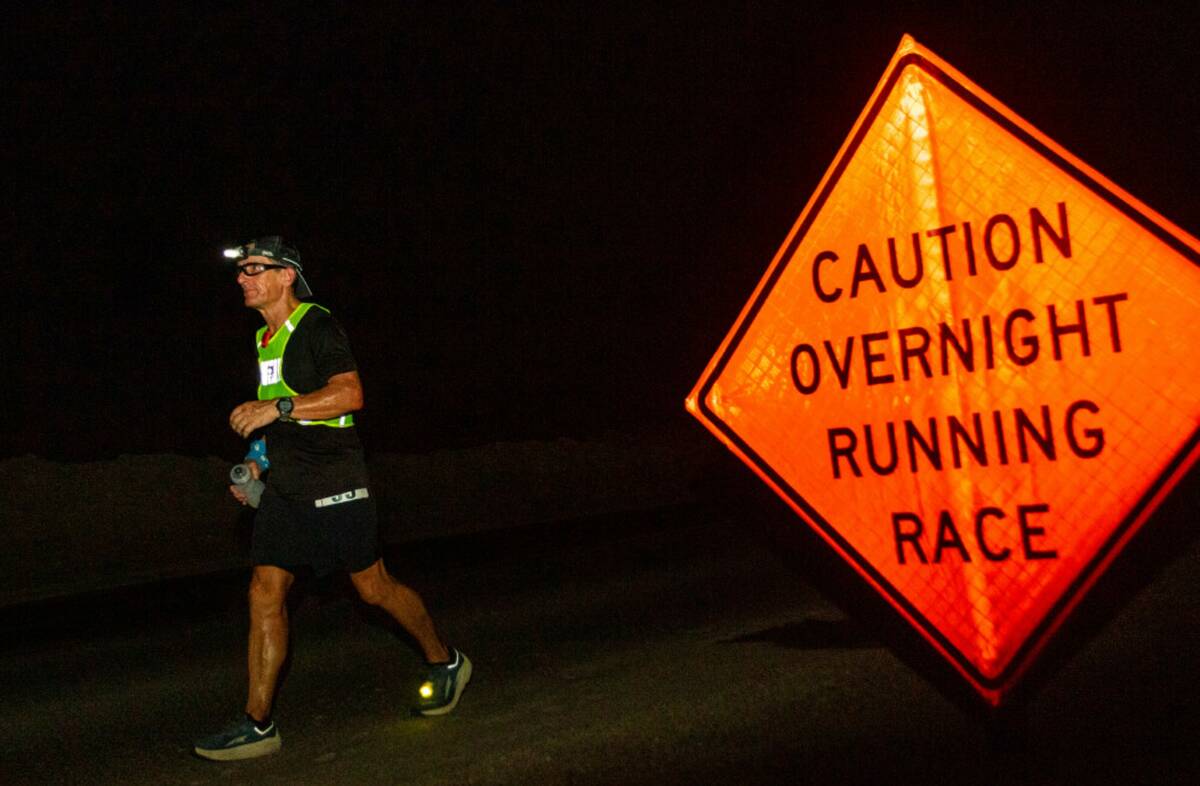 A runner passes by a sign warning traffic of the race on Route 66 during the Badwater 135 mile ...