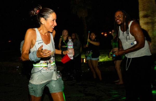 The self proclaimed "Death Valley cheerleaders" cheer and spray water at runner Caryn Lubetsky, ...