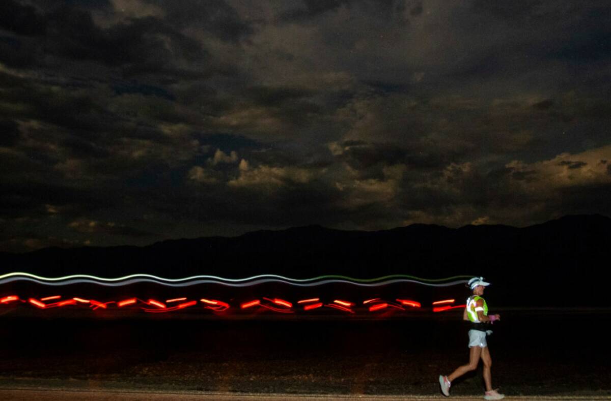 A runner races with a headlamp and a safety vest under a moon light sky during the Badwater 135 ...