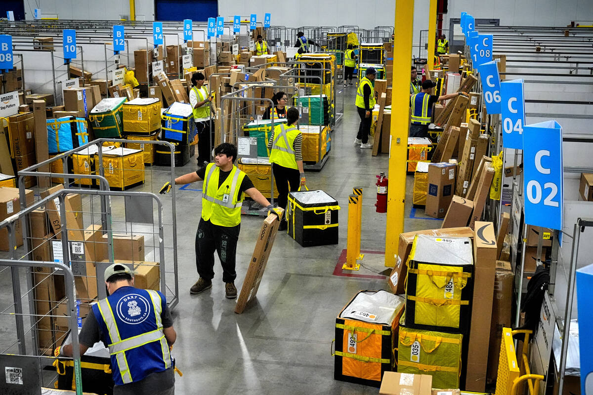FILE - Amazon employees load packages on carts before being put on to trucks for distribution f ...