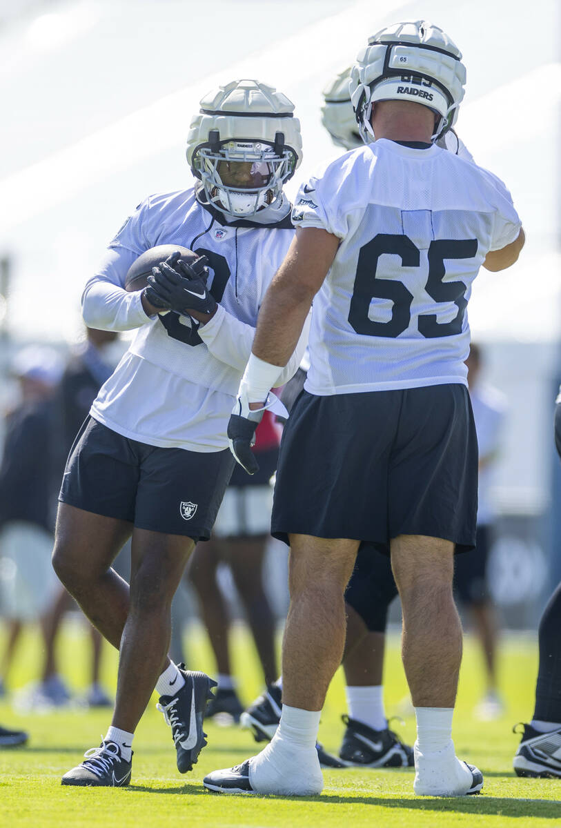 Raiders running back Zamir White (3) bumps into guard Cody Whitehair (65) as he runs the ball o ...