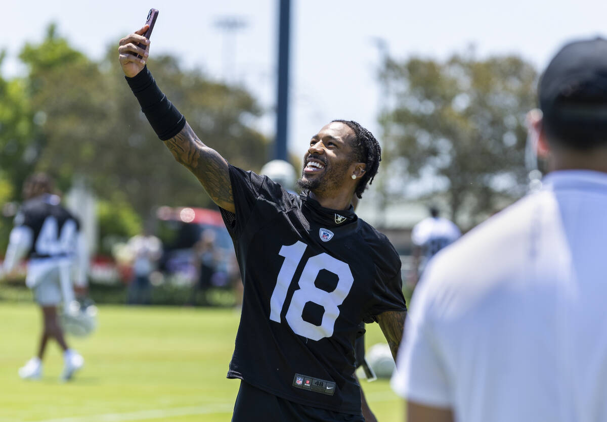 Raiders cornerback Jack Jones (18) takes a selfie with fans in the background on the way to a m ...