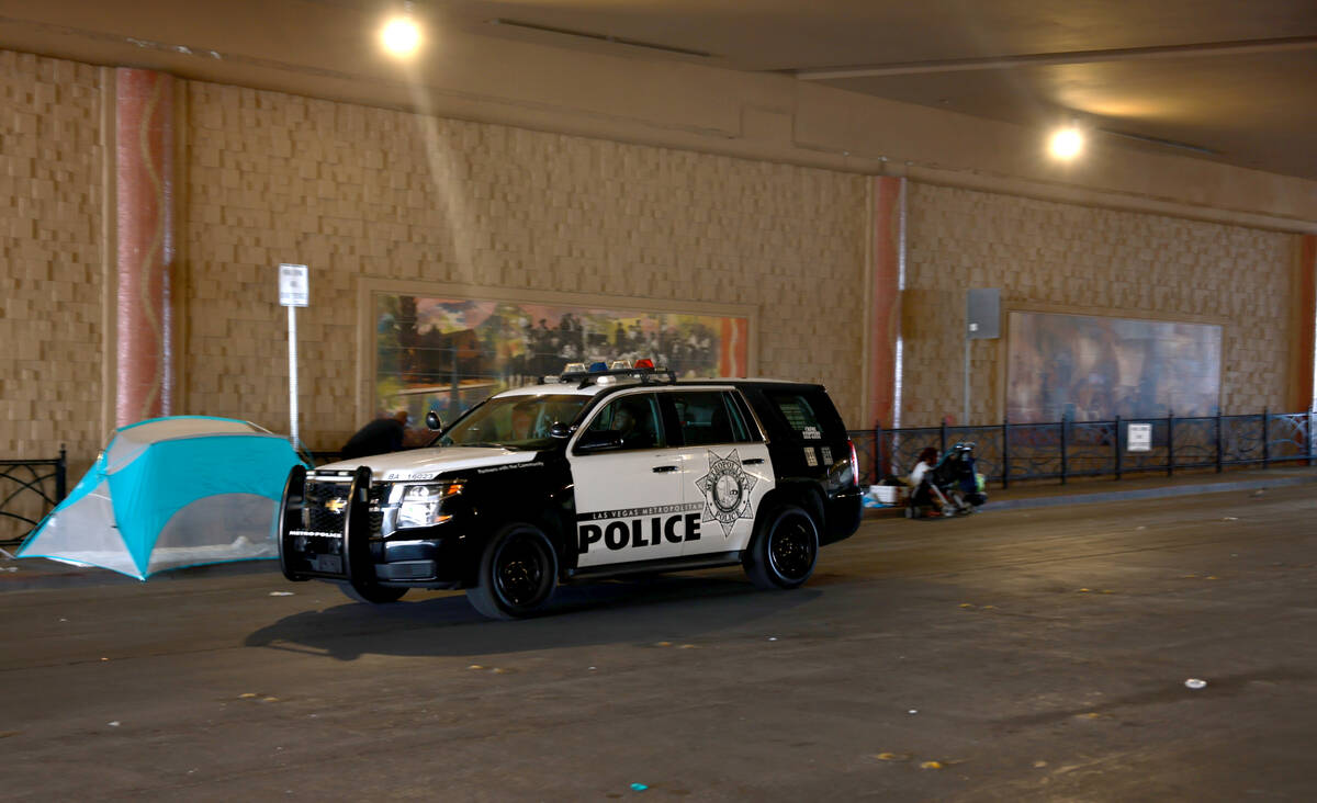 A Las Vegas police officer drives past tents on F Street under Interstate 15 in Las Vegas Thurs ...