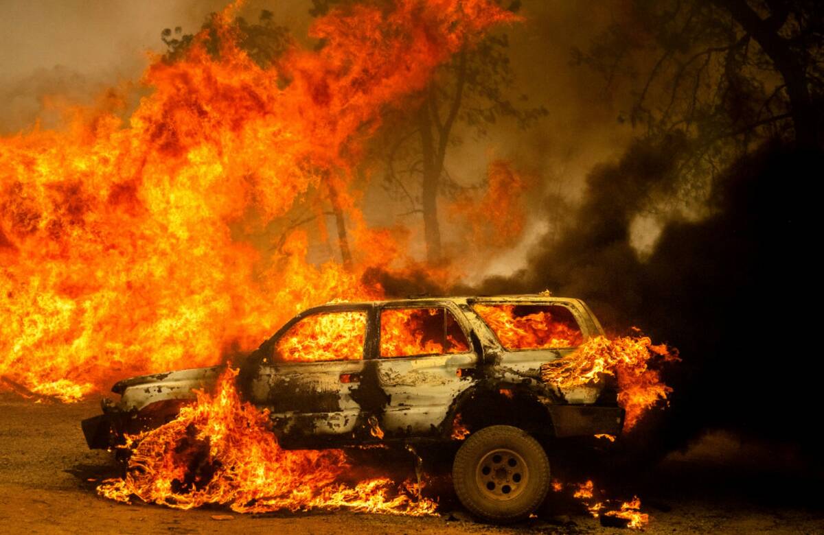 Flames consume a car and building as the Park Fire tears though the Cohasset community in Butte ...