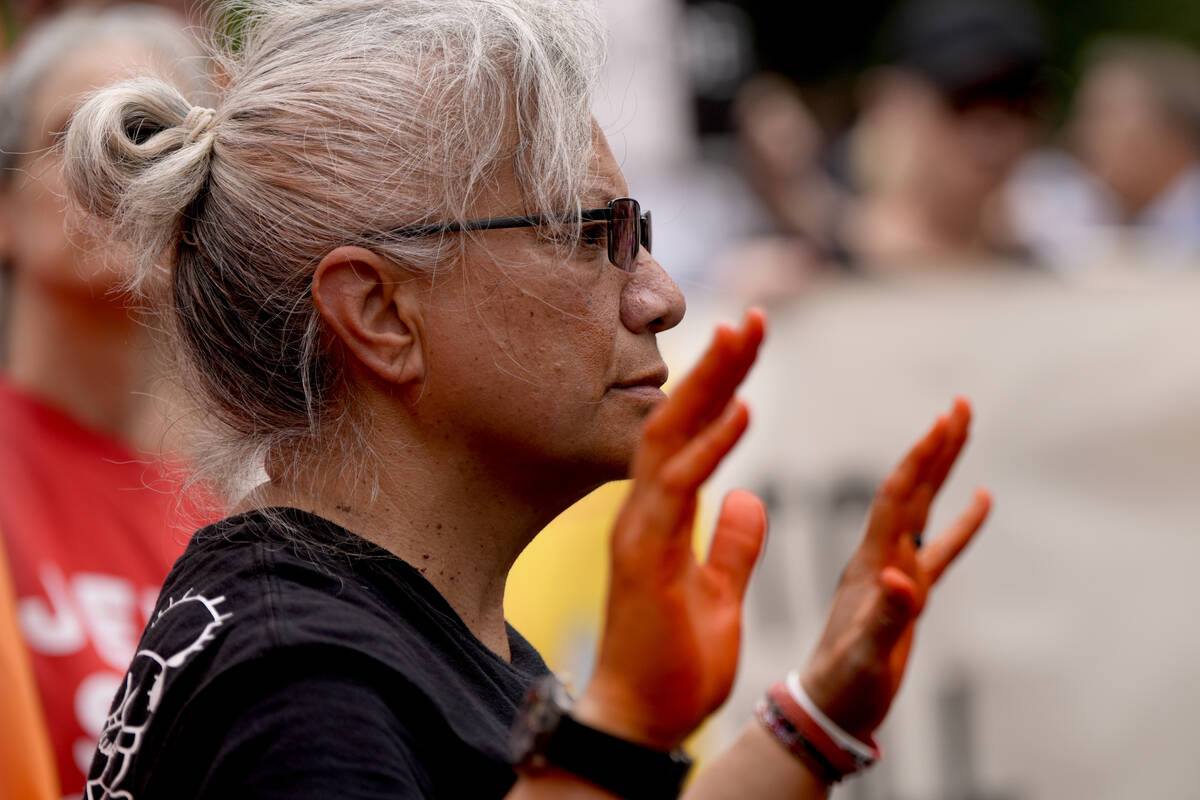 A demonstrator holds up their hands stained with a red liquid as Hasidic Jews and others protes ...