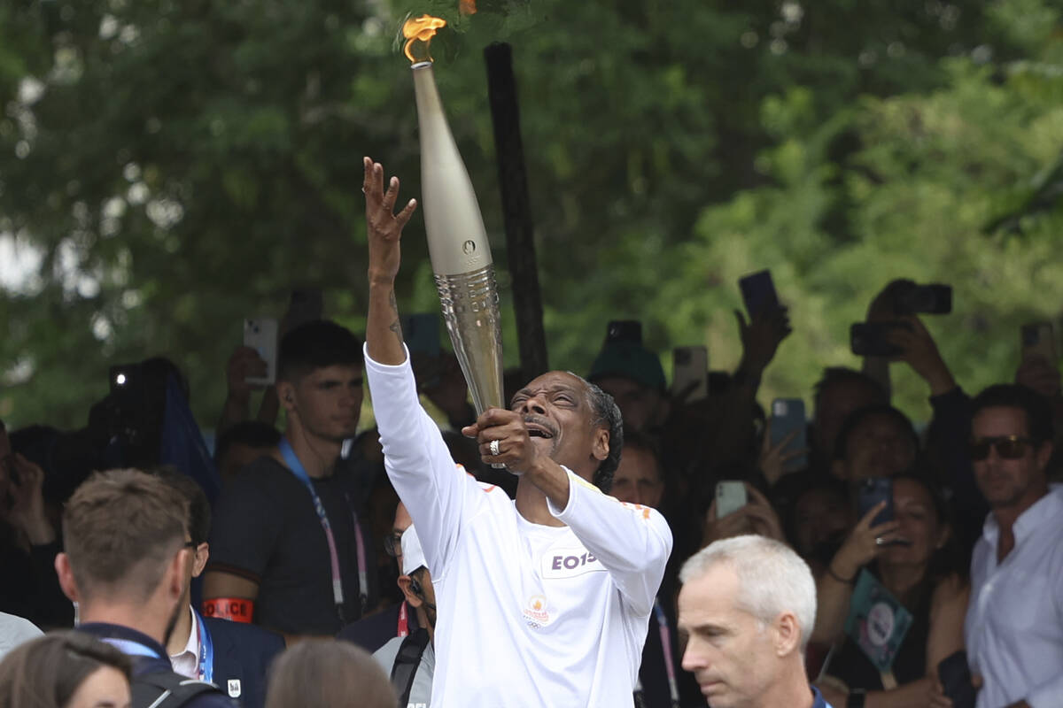 Snoop Dogg carries the Olympic torch at the 2024 Summer Olympics, Friday, July 26, 2024, in Sai ...