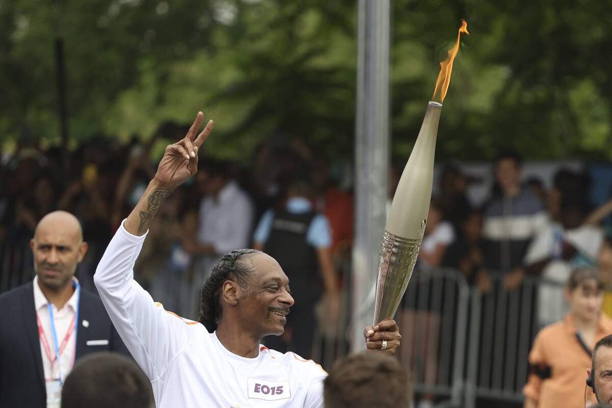 Snoop Dogg carries the Olympic torch at the 2024 Summer Olympics, Friday, July 26, 2024, in Sai ...