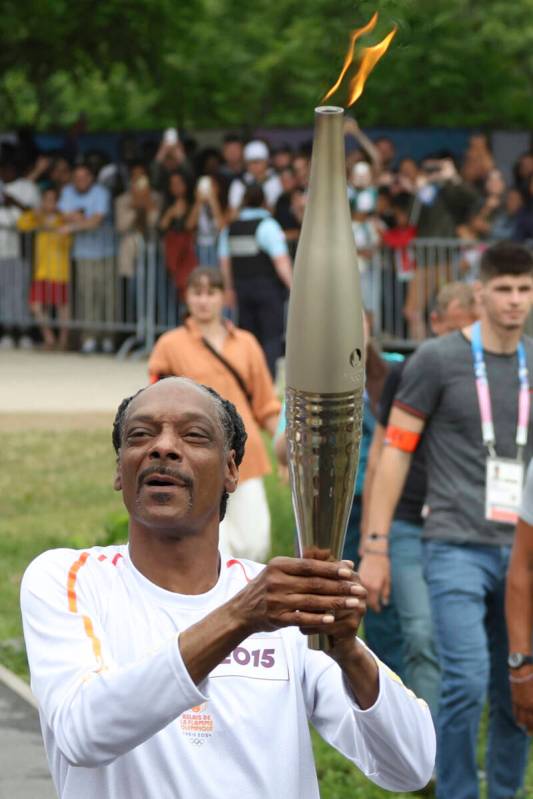 Snoop Dogg carries the Olympic torch at the 2024 Summer Olympics, Friday, July 26, 2024, in Sai ...