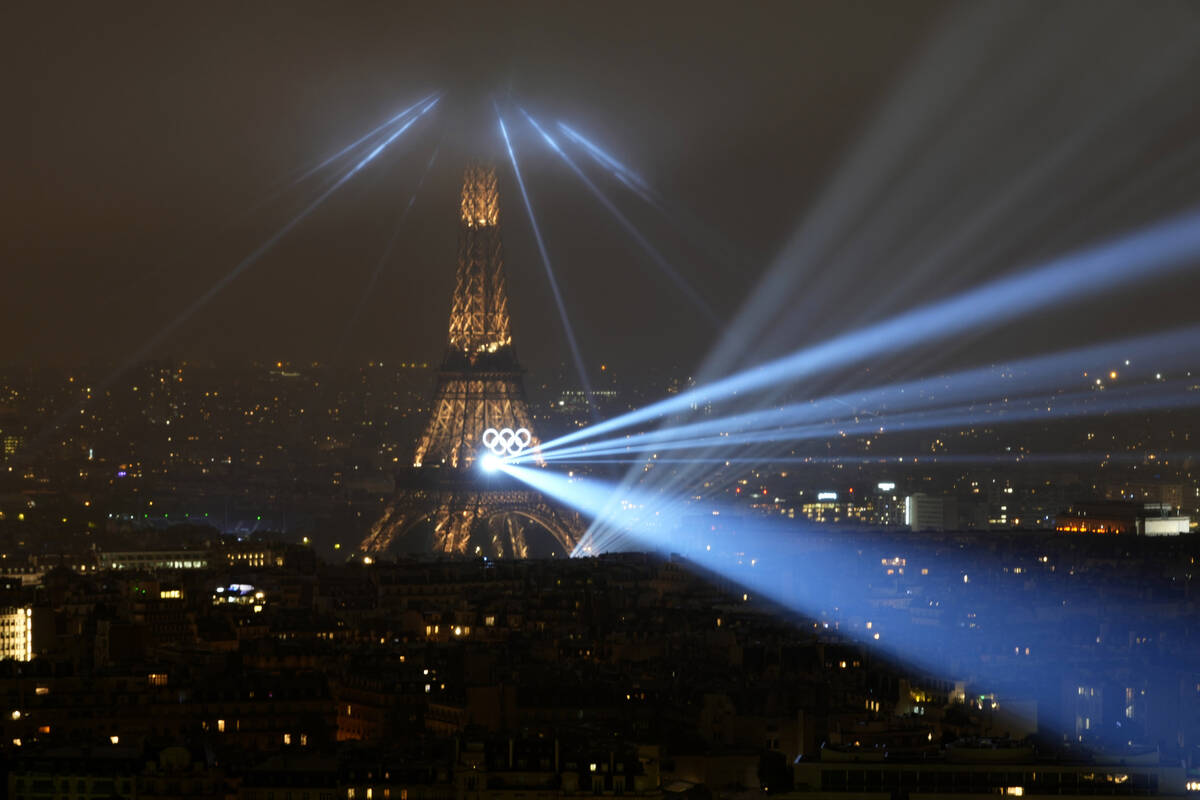 A light show is projected from the Eiffel Tower in Paris, France, during the opening ceremony o ...
